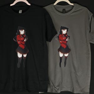 May include: Two t-shirts with a black and a gray background. Both shirts feature a printed image of a female anime character with black hair, a red dress, and black stockings. The character is standing with her arms crossed.