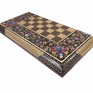 May include: A black wooden chessboard with a floral inlay design. The board is decorated with intricate patterns of flowers and leaves in shades of gold, red, blue, and white. The chessboard is made of wood and has a glossy finish.
