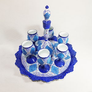 Puede incluir: Un juego de seis tazas de cerámica pintadas a mano en azul y blanco y una jarra a juego en una bandeja decorativa. Las tazas y la jarra tienen intrincados diseños florales.