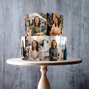 May include: A two-tiered cake with a photo collage design, displayed on a light wood cake stand. The cake features images of a woman in various settings. The stand has a round top and a pedestal base. The cake stand is made in the UK.