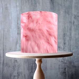May include: A pink cake with a fluffy, fur-like texture sits on a light wood cake stand. The stand has a round top and a pedestal base. The cake stand is approximately 10 inches in diameter. The image includes a "Made in the UK" sticker and a "Vegan" sticker.