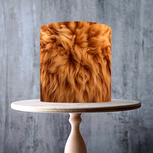 May include: A cylindrical cake with a textured, brown fur-like design sits on a light-colored wooden cake stand. The stand has a round top, a turned pedestal, and a circular base. The background is a mottled gray. The image includes a "Made in the UK" logo and a "Vegan, Gluten Free" logo.