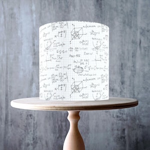 Może przedstawiać: Cylindryczny klosz lampy z białym tłem pokrytym równaniami i diagramami matematycznymi, umieszczony na jasnym drewnianym stojaku na ciasto. Stojak ma okrągły blat i podstawę. Wyprodukowano w Wielkiej Brytanii.
