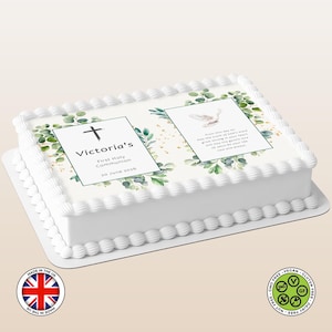 May include: A white rectangular cake decorated for a First Holy Communion. The cake features text that reads "Victoria's First Holy Communion 30 June 2026" and a dove illustration. Greenery and gold accents surround the text and image.