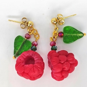 May include: Gold-coloured stud earrings with red raspberry charms. Each earring has a green leaf and a cluster of small, colourful beads. The raspberries are a vibrant red, and the leaves are a translucent green.