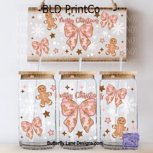 May include: Clear glass tumblers with bamboo lids and straws, decorated with pink bows, gingerbread men, snowflakes, and stars. A matching sign above reads "Merry Christmas".