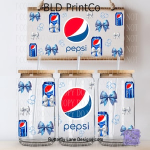 May include: Clear glass beverage cups with bamboo lids, featuring Pepsi logos and soda can designs with blue bows. A matching wooden sign with Pepsi branding and bows hangs above. The text "Butterfly Lane Designs.com" is visible.