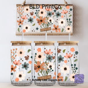 May include: Three clear glass tumblers with bamboo lids and straws, decorated with floral designs in shades of orange, white, and teal. A matching sign with the text "BLD PrintCo" hangs above. The website "Butterfly Lane Designs.com" is visible.