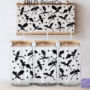 May include: Three clear glass tumblers with bamboo lids and straws, featuring a black dragon and star pattern. A matching wooden sign with the text "BLD PrintCo" and a dragon design hangs above. The website "Butterfly Lane Designs.com" is visible.