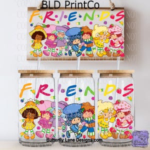 May include: Clear glass tumblers with wooden lids and straws, featuring the word "FRIENDS" in colorful letters and cartoon characters. A matching wooden sign with the same design hangs above the tumblers. The text "BLD PrintCo" and "Butterfly Lane Designs.com" are also visible.