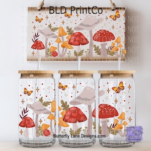 May include: Three clear glass tumblers with wooden lids and straws, featuring a whimsical mushroom and butterfly design. A matching wooden sign hangs above, also decorated with mushrooms and butterflies. The text "BLD PrintCo" is visible on the sign.