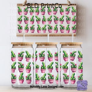 May include: Three clear glass tumblers with bamboo lids and straws, featuring a repeating pattern of green cactus plants in pink pots. A wooden sign with the same pattern hangs above the tumblers. Text on the sign reads "BLD PrintCo" and "Butterfly Lane Designs.com".