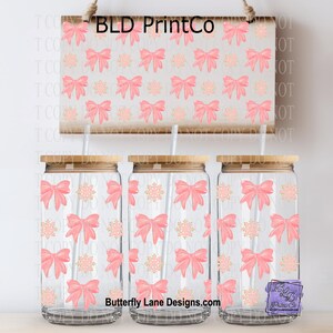 May include: Three glass tumblers with bamboo lids and straws, decorated with pink bows and gold snowflakes. A sign above displays the same pattern with the text "BLD PrintCo". The tumblers are clear and have a capacity of approximately 16 ounces.