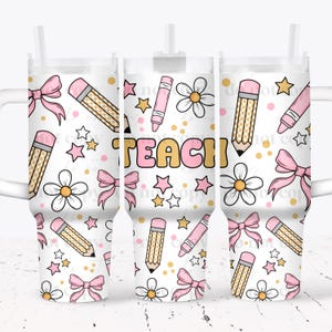 May include: White tumbler with a repeating pattern of pink bows, pencils, flowers, stars, and the word "TEACH" in yellow and pink. The tumbler has a white handle and a straw.