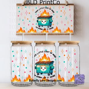 May include: Clear glass beverage cups with bamboo lids, featuring a design of a smiling teal dumpster with flames and the text "This Little Light of Mine, I'm Gonna Let It Shine." The design includes colorful stars and dots.