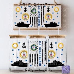 May include: Three clear glass tumblers with bamboo lids and straws, featuring a U.S. Coast Guard design. The design includes a flag, stars, anchors, and the text "U.S. Coast Guard". A wooden sign with the same design hangs above the tumblers.