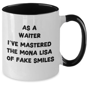 May include: White ceramic mug with a black interior and handle. The mug features the text "AS A WAITER I'VE MASTERED THE MONA LISA OF FAKE SMILES" in black, bold font.
