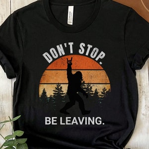 K&ouml;nnte beinhalten: Schwarzes T-Shirt mit einem Retro-Sonnenuntergang-Motiv und einer Silhouette von Bigfoot mit dem Text "Don't Stop. Be Leaving."