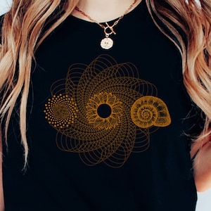 May include: A black t-shirt with a gold geometric design featuring a spiral, a circle, and a seashell.
