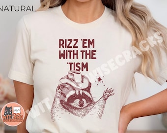 May include: A white t-shirt with a brown raccoon wearing a cowboy hat and the text "Rizz 'em with the 'tism" in maroon.