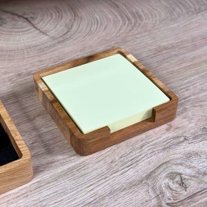 Könnte beinhalten: Ein hölzerner Schreibtisch-Organizer mit einem integrierten Notizblockhalter. Der Notizblockhalter ist aus hellbraunem Holz gefertigt und enthält einen hellgrünen Notizblock.