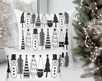 May include: Three white rectangular throw pillows with a black and white Christmas design. The design includes snowmen, Christmas trees, and Santa Claus figures. The pillows are arranged on a windowsill with a Christmas tree in the background.