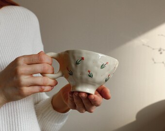 Taza de cerámica única hecha a mano con un delicado patrón floral.
