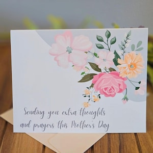 May include: A light blue card with a floral design and the text "Sending you extra thoughts and prayers this Mother's Day."