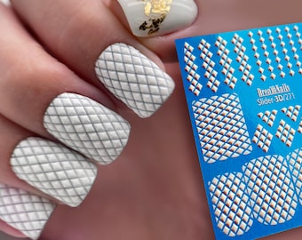 May include: White nail polish with a 3D diamond grid pattern. The nail polish is shown on a hand with a blue sheet of nail art stickers with the text "DreamNails Slider 3D/271".