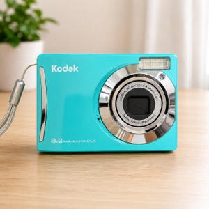 以下が含まれることがあります： 鮮やかなターコイズブルーのKodak製デジタルカメラ。8.2 megapixelsのラベル、シルバーのリストストラップ、Kodak AF 3x Optical Aspheric Lens 36mm-108mm Equivalentと刻印されたレンズを備えています。本体は長方形で、シルバーのフラッシュユニットが付いています。