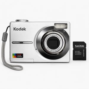 以下が含まれることがあります： リストストラップ付きのシルバーのKodakデジタルカメラと、黒いSanDisk microSDアダプター。カメラには「Kodak AF 3x Optical Aspheric Lens 36mm-108mm」と記されたレンズ、フラッシュ、および前面にKodak Color Scienceのロゴが配置されています。