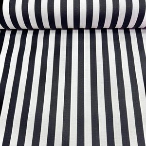 May include: Black and white striped fabric. The fabric is rolled up, showing the pattern of vertical stripes. The stripes alternate between black and white, creating a bold, graphic design. The fabric appears to be a medium weight material.