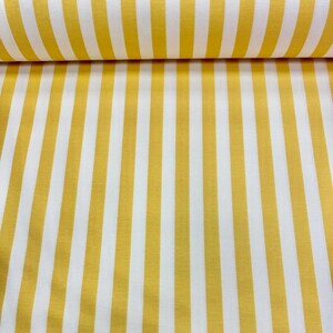 May include: Yellow and white striped fabric. The fabric features vertical stripes of a bright yellow color alternating with white stripes. The fabric is rolled up at the top, showing the texture and pattern of the material.