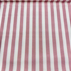 May include: Fabric with a repeating pattern of vertical stripes in white and dusty rose. The stripes are evenly spaced and run the length of the fabric. The fabric appears to be folded over at the top.