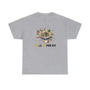 May include: A heather gray t-shirt featuring a colorful illustration of a bowl of pho with various ingredients. The text "my oh my PHO KIT" is printed below the graphic in yellow and white.