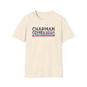 May include: A beige t-shirt with a distressed black graphic that reads "Chapman Combs 2024" and the text "Maybe together we can get somewhere" in red, white, and blue.