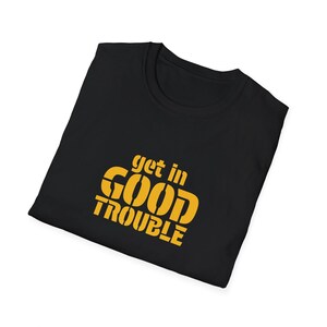 May include: Black t-shirt with the text "get in GOOD TROUBLE" printed in yellow.