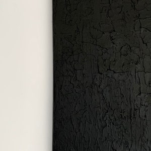 Könnte beinhalten: Schwarzes Leinwandbild mit einer strukturierten Oberfläche, die an rissige Erde erinnert.