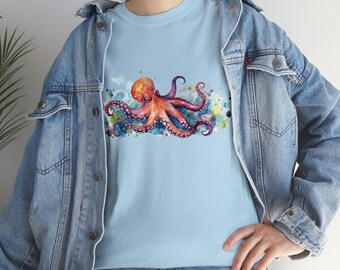 May include: A light blue t-shirt featuring a watercolour illustration of an octopus with pink and orange tentacles. The octopus is surrounded by colourful watercolour splatters.