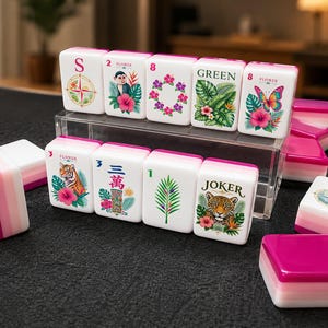 May include: A set of white Mahjong tiles with pink backs, featuring colorful tropical illustrations of flowers, leaves, a tiger, a monkey, a leopard, and a butterfly. Some tiles display the letters S, N, the word GREEN, JOKER, and numbers.