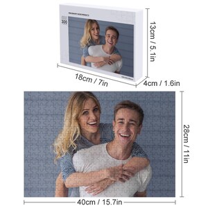 May include: A 300-piece jigsaw puzzle featuring a couple smiling and hugging. The puzzle is 40 cm wide and 28 cm tall.