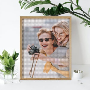 May include: A framed photo of two people smiling and taking a picture with a camera. The photo is in a wooden frame and the people are wearing sunglasses.