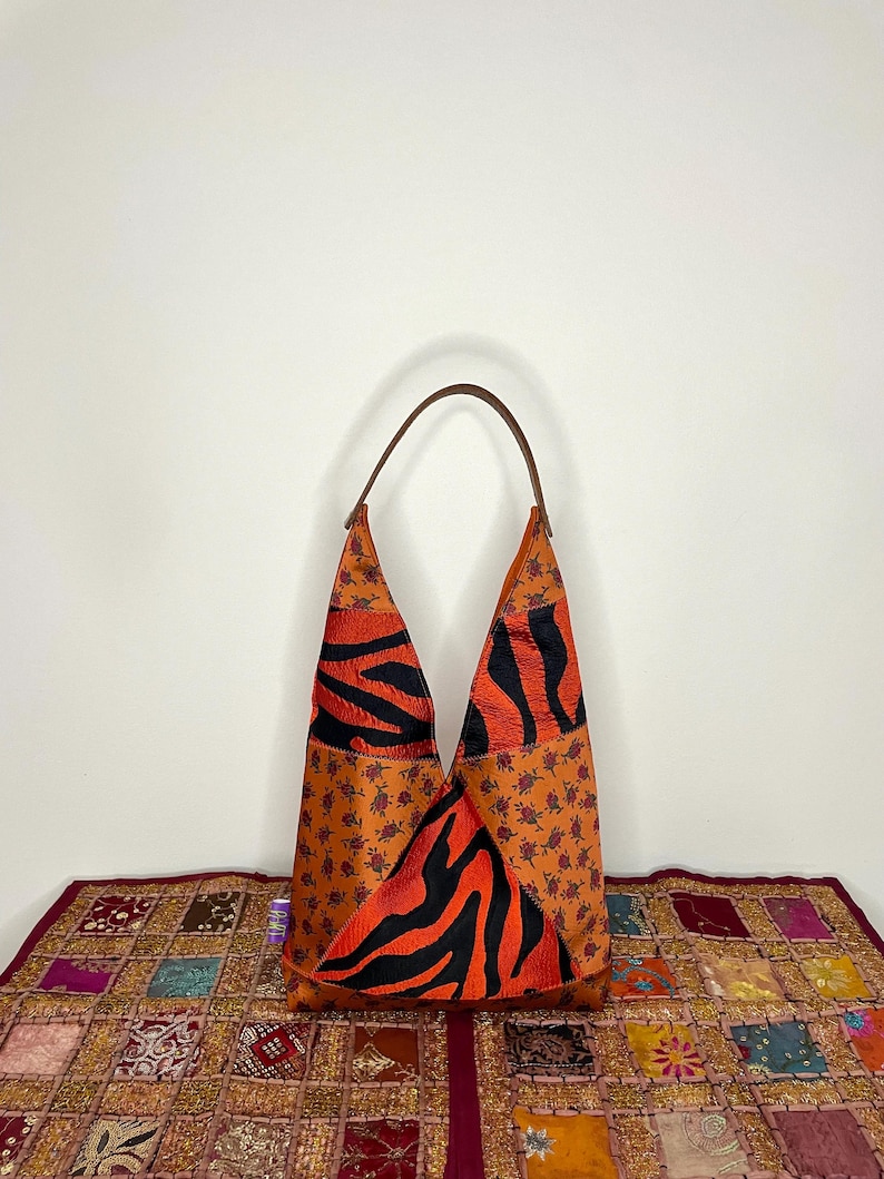 Pode incluir: Uma bolsa tote de couro marrom com um design de estampa de zebra. A bolsa tem uma al&ccedil;a &uacute;nica e &eacute; feita de um mosaico de diferentes tecidos.