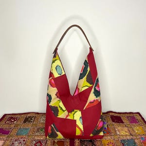 May include: A red patchwork tote bag with a brown leather handle. The bag features a geometric pattern with yellow, green, and pink accents.