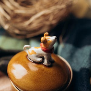 Handcrafted ceramic keepsake container with removable dog-topped lid in warm fall colors, navy blue base with saucer, ideal Secret Santa gift for pet enthusiasts and jewelry storage