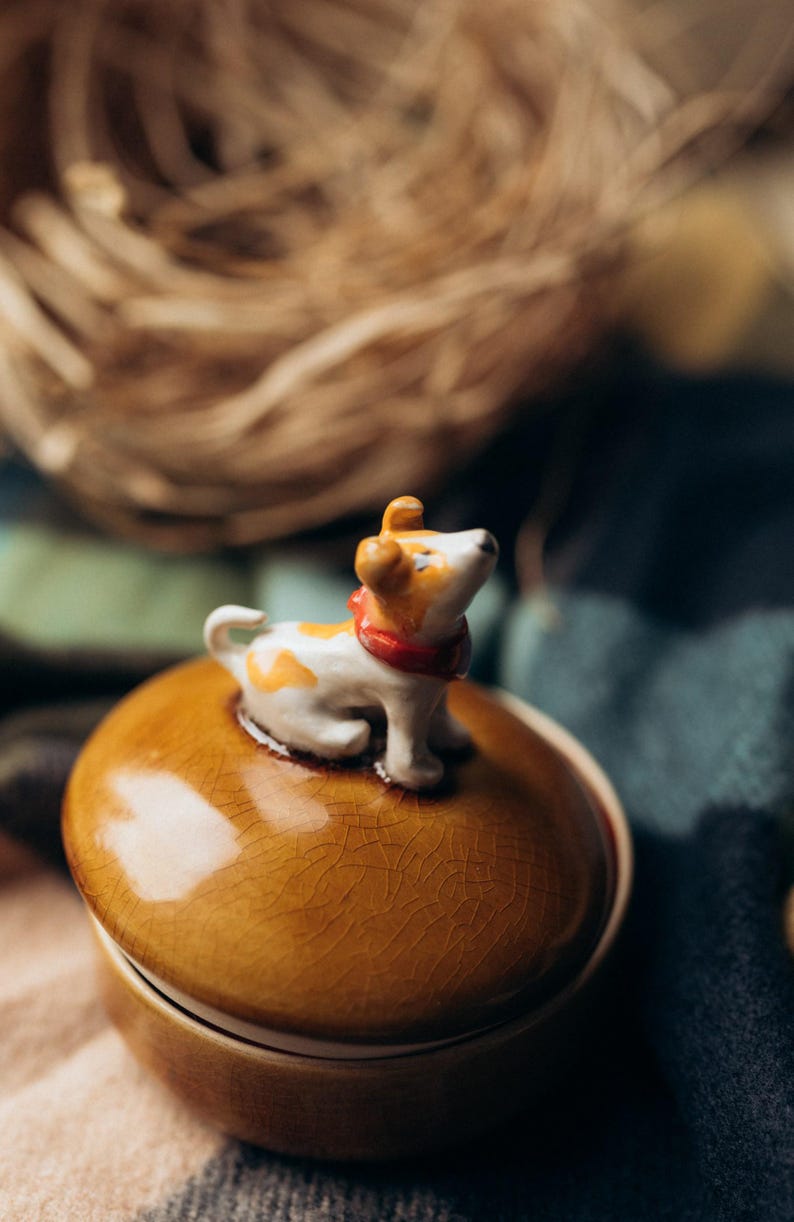 Handcrafted ceramic keepsake container with removable dog-topped lid in warm fall colors, navy blue base with saucer, ideal Secret Santa gift for pet enthusiasts and jewelry storage