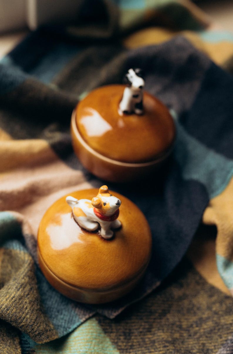 Unique pottery trinket box with black and white dog figurine sitting on orange crackle glazed lid, deep blue cup-style base, autumn home decor piece for storing rings and small treasures