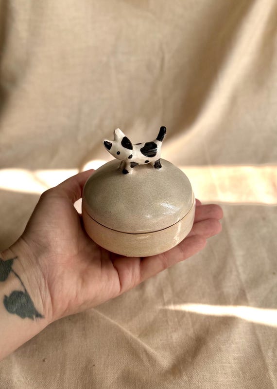 A ceramic jewelry box where the LID IS A DOG — hand-sculpted, functional, and instantly conversation-starting on any vanity.
