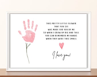 May include: A pink handprint in the shape of a flower with a green stem and leaves. The text reads: "This pretty little flower that you see was made for you by me so when I grow up big and tall you can remember my hands when they were this small. I love you!"