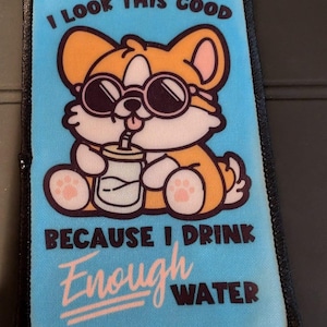 May include: A blue and orange patch with a cartoon dog wearing sunglasses and drinking from a glass with a straw. The text on the patch reads "I look this good because I drink enough water".
